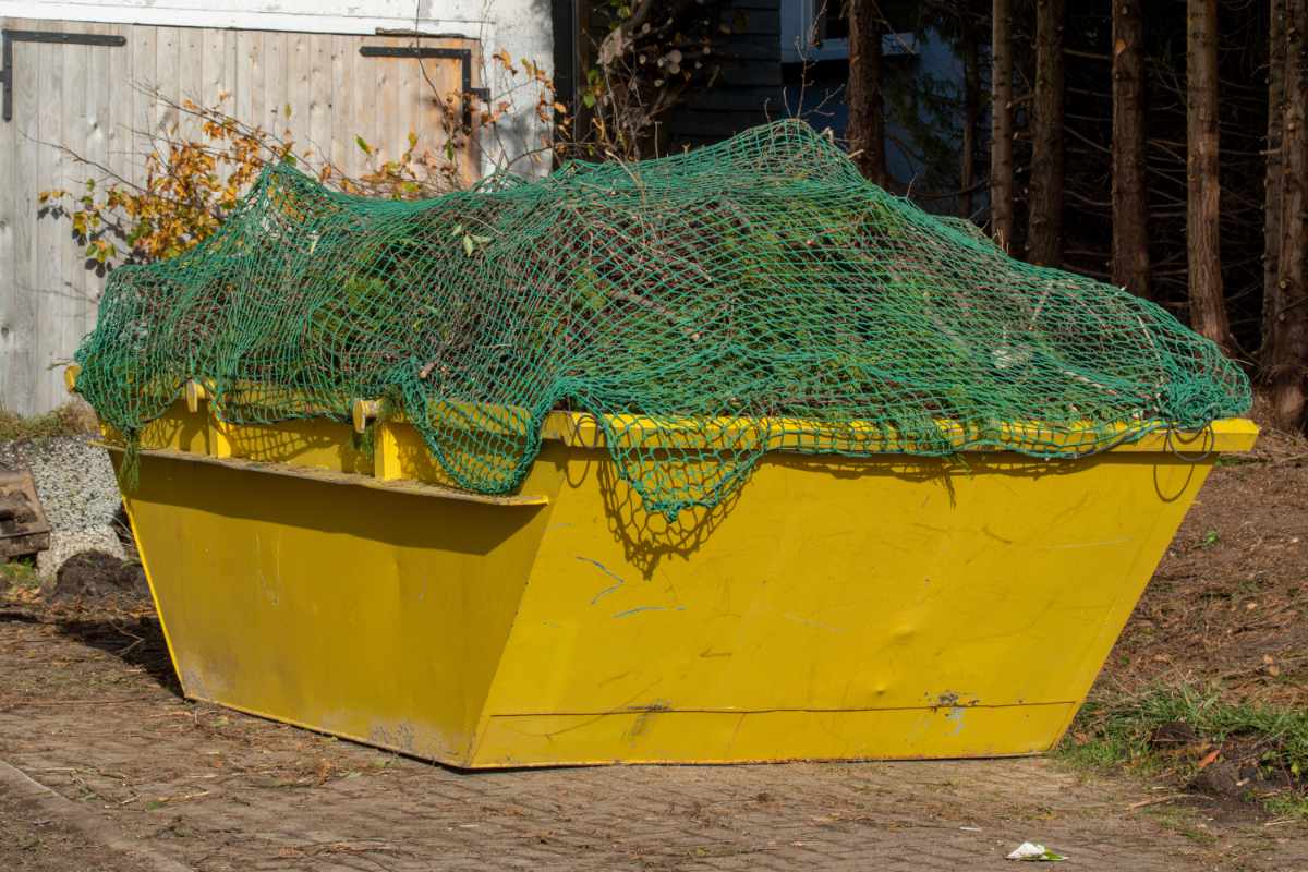 A yellow skip, container is loaded with garden waste