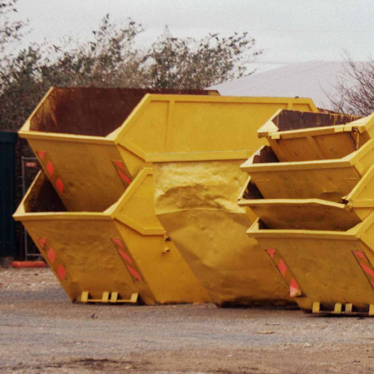 Multiple yellow skips pilled in a waste field.
