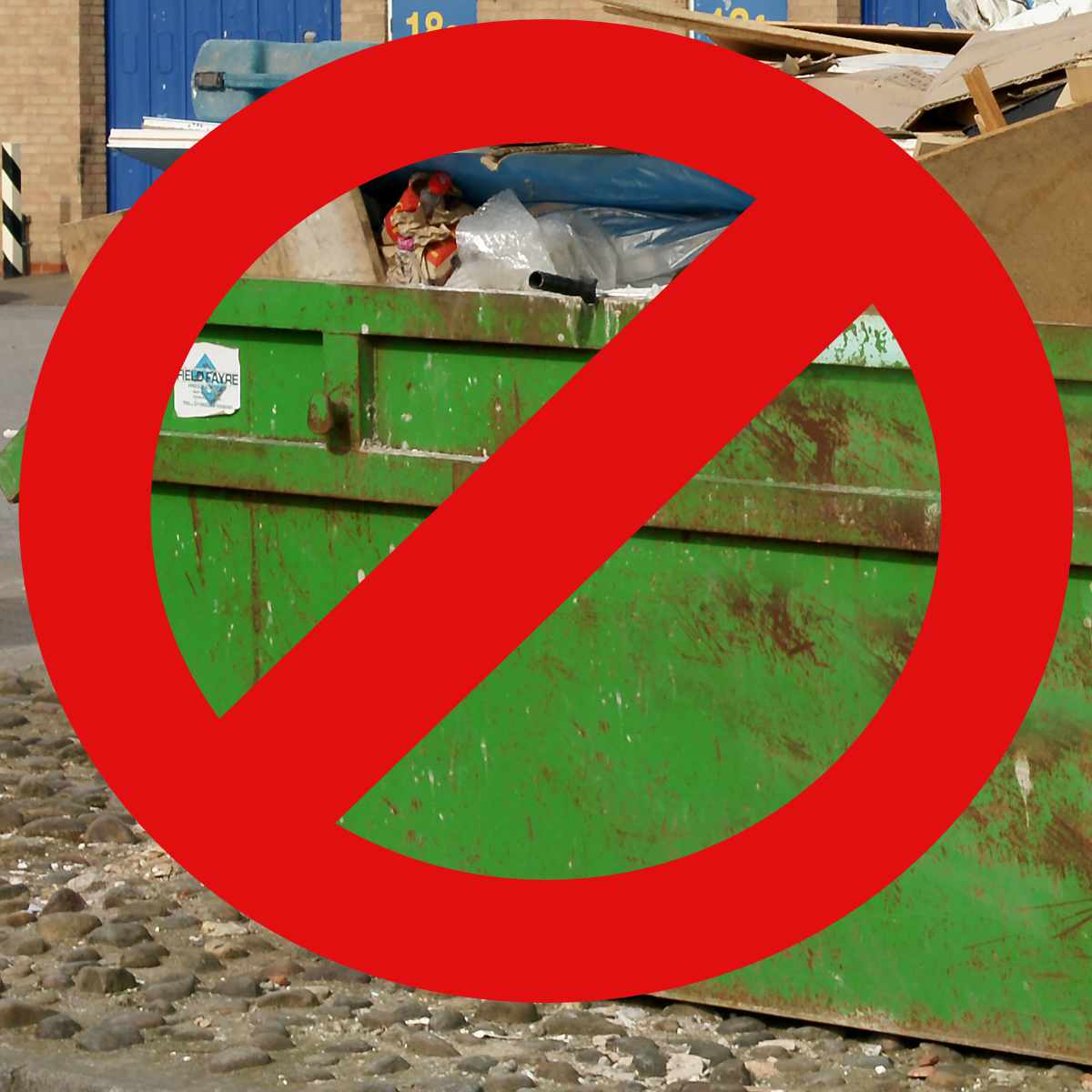 A green skip on a street with a prohibited warning.