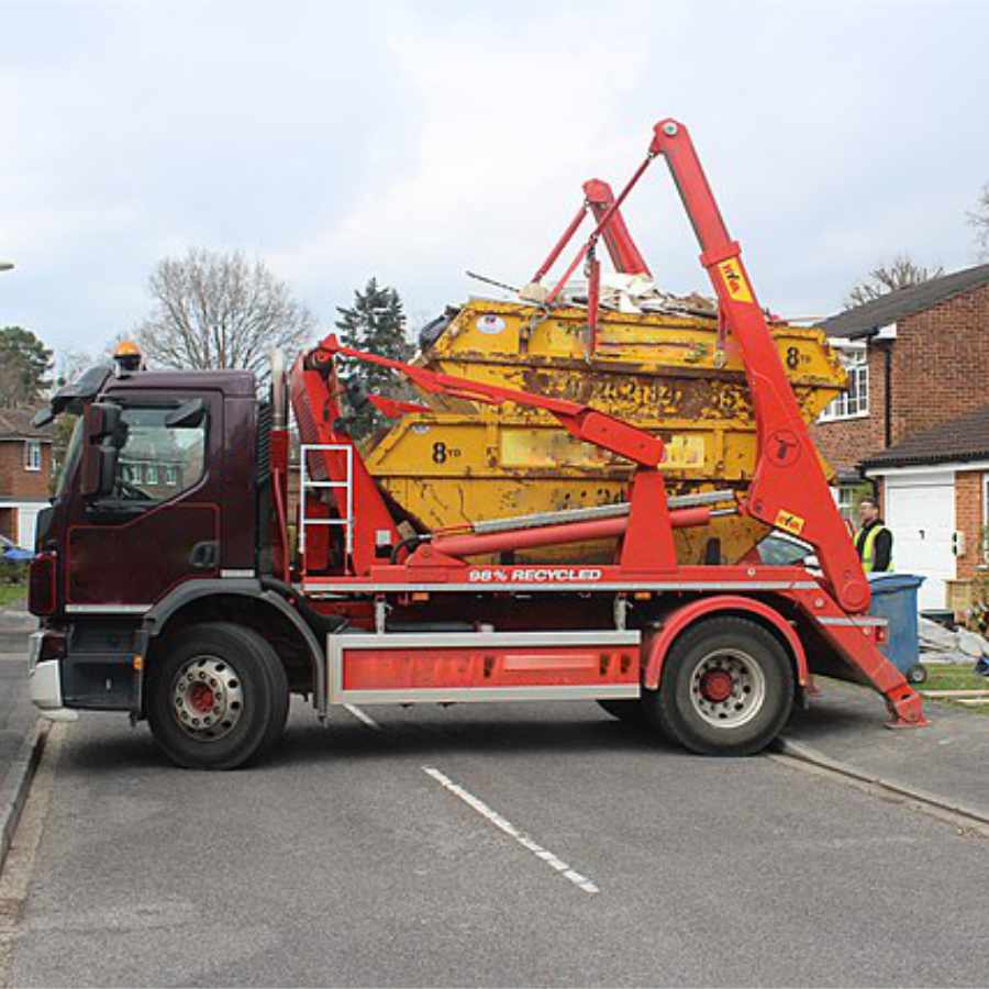 red skip hire truck offloading two large skip in a road in nottingham.