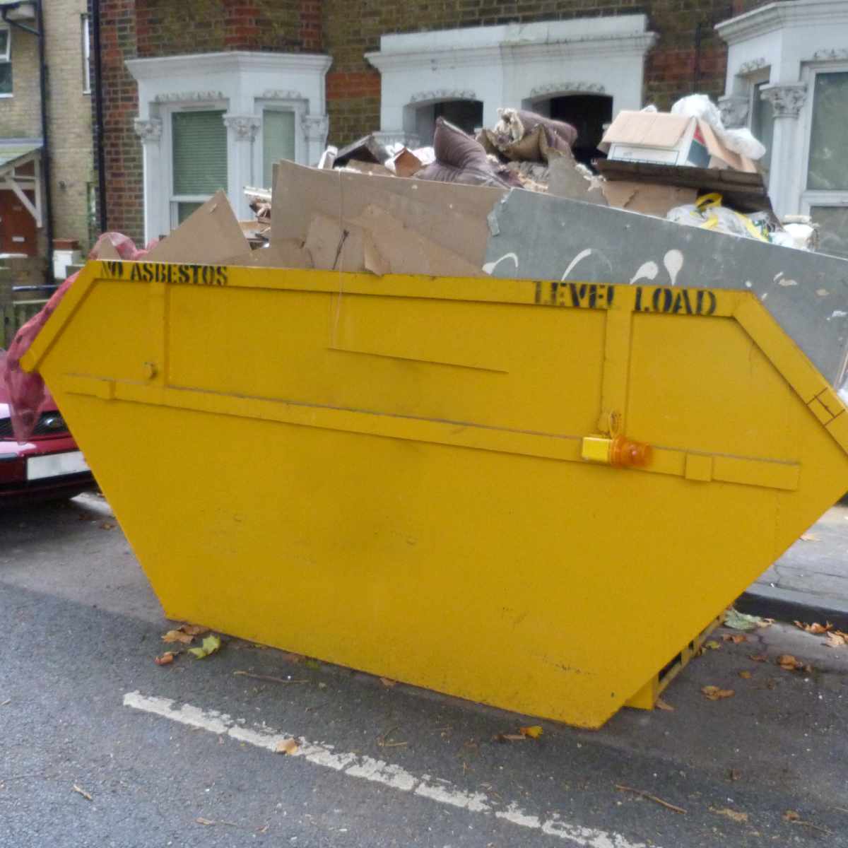 A yellow skip bin on a road outside a house in nottingham.